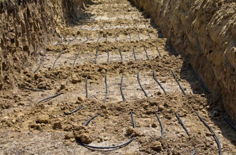 A dirt trench with plastic tubing use for geothermal energy laid out in rows